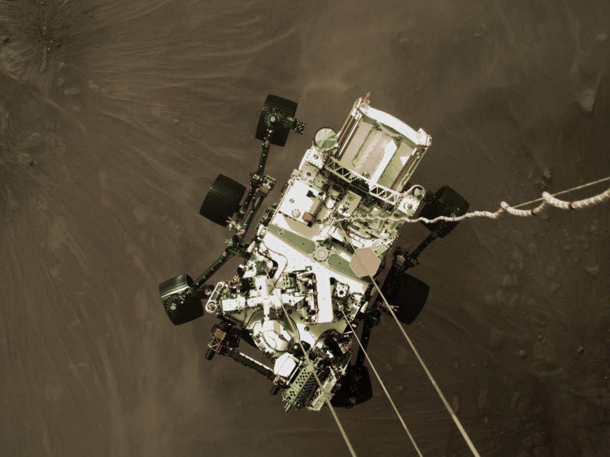Widok w dół z lądownika na podwieszony pod nim łazik tuż przed dotknięciem powierzchni Marsa